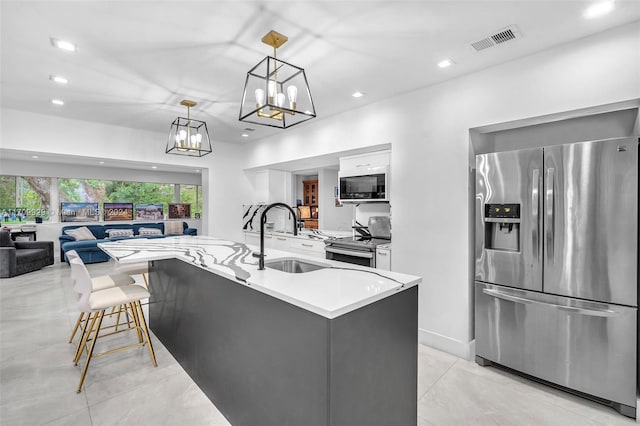 kitchen with pendant lighting, a center island with sink, sink, appliances with stainless steel finishes, and a kitchen bar