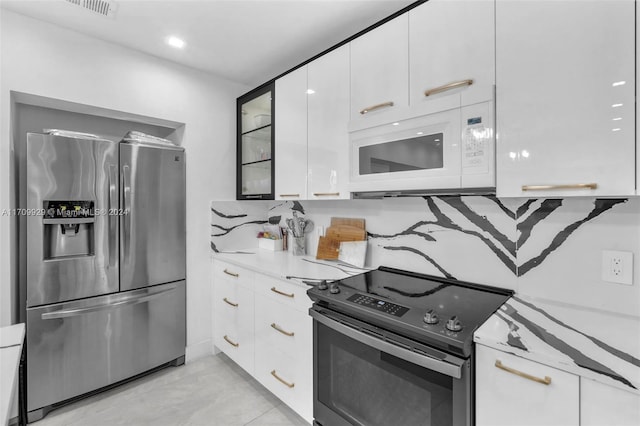 kitchen featuring backsplash, white cabinets, stainless steel appliances, and light tile patterned floors