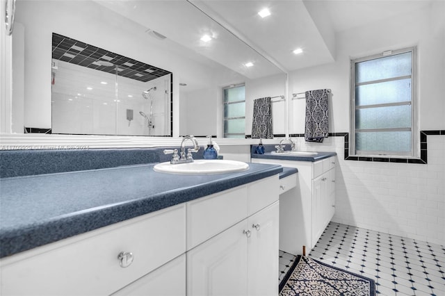 bathroom featuring tile patterned floors, vanity, a tile shower, and tile walls