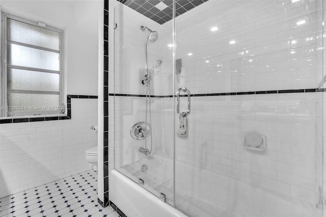 bathroom with tile patterned flooring, toilet, tiled shower / bath, and tile walls