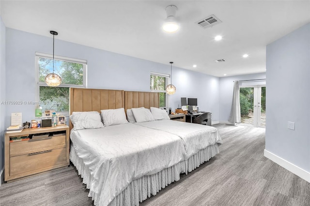 bedroom with hardwood / wood-style flooring, access to outside, and multiple windows