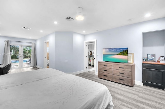 bedroom with access to outside, a spacious closet, french doors, and light hardwood / wood-style flooring