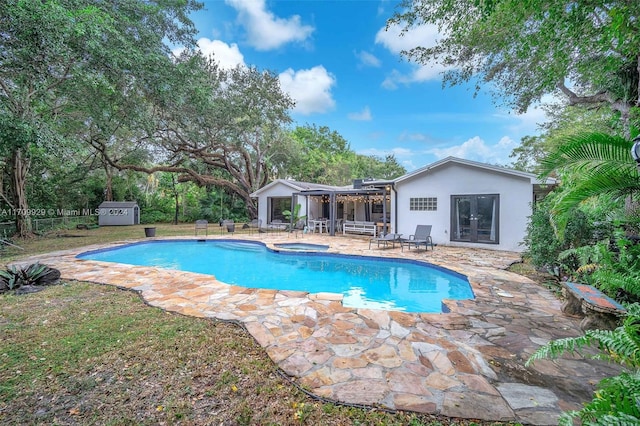 view of swimming pool with a patio area, an in ground hot tub, and a storage shed