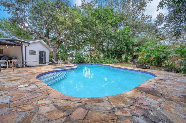 view of swimming pool with a patio area and an in ground hot tub