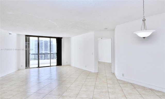 empty room featuring light tile patterned floors, a textured ceiling, and a wall of windows