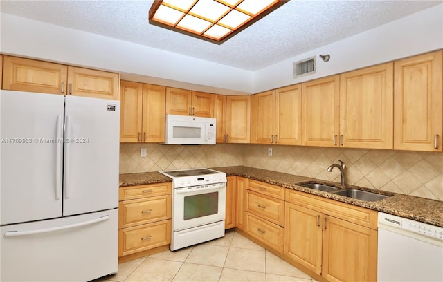 kitchen featuring tasteful backsplash, dark stone counters, a textured ceiling, white appliances, and sink