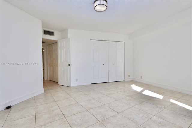 unfurnished bedroom with light tile patterned floors, a textured ceiling, and a closet