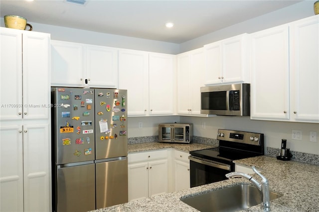 kitchen featuring white cabinets, light stone counters, sink, and appliances with stainless steel finishes