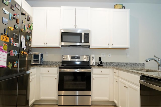 kitchen with white cabinetry, light stone countertops, sink, and stainless steel appliances