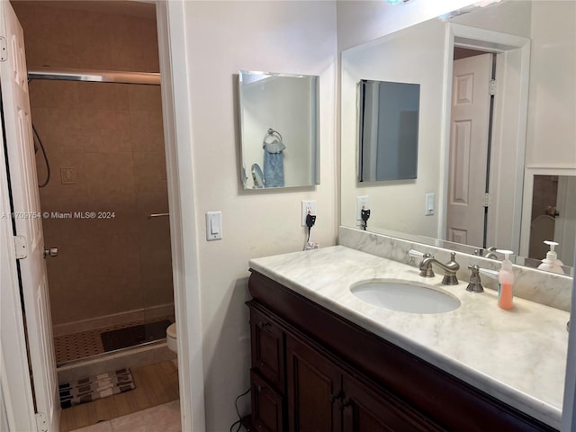 bathroom with tile patterned floors, vanity, toilet, and a tile shower