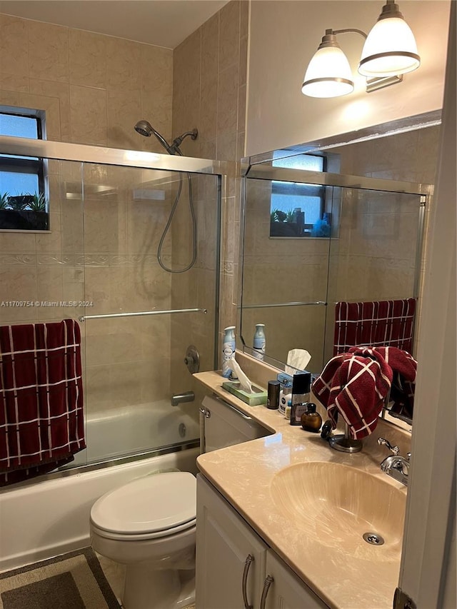 full bathroom with vanity, toilet, and enclosed tub / shower combo