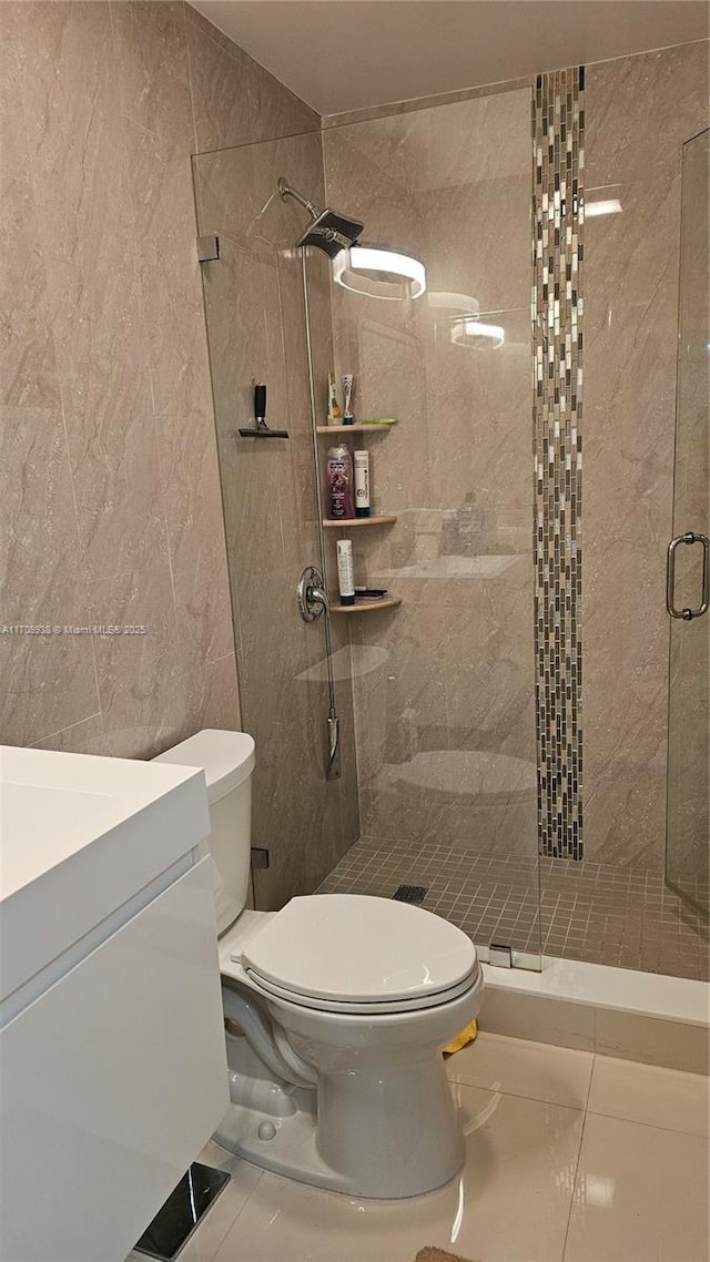 bathroom featuring toilet, a shower stall, tile walls, and vanity