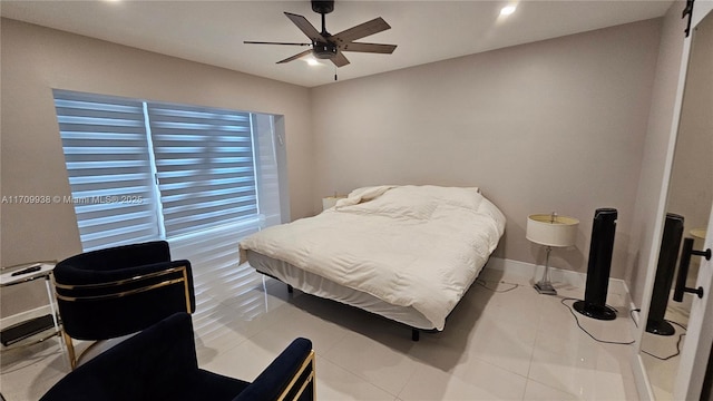 bedroom with ceiling fan, baseboards, and a barn door