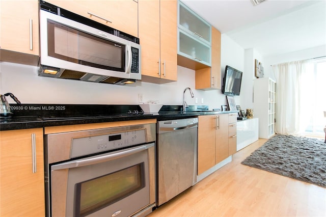 kitchen with sink, appliances with stainless steel finishes, light hardwood / wood-style flooring, and light brown cabinets