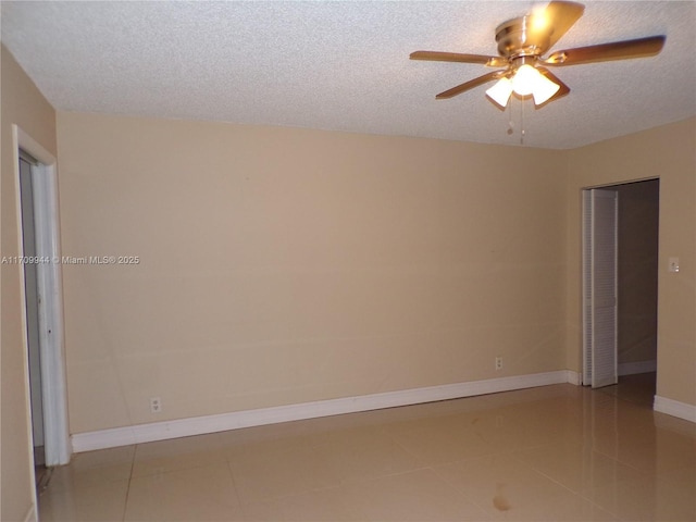 spare room with ceiling fan, light tile patterned floors, and a textured ceiling