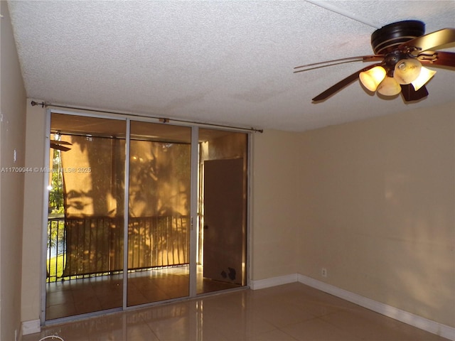 tiled spare room featuring ceiling fan, a textured ceiling, and a wall of windows