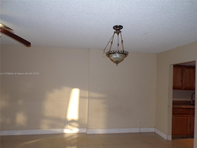 unfurnished dining area featuring light tile patterned floors, a textured ceiling, and ceiling fan