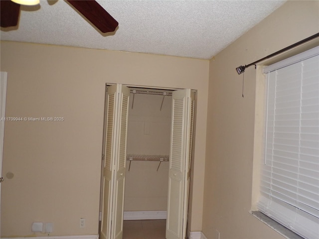 unfurnished bedroom with a textured ceiling, a closet, and ceiling fan