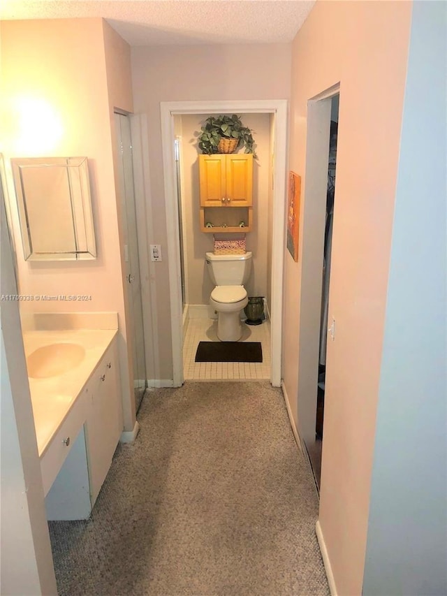 bathroom with vanity, toilet, and a textured ceiling