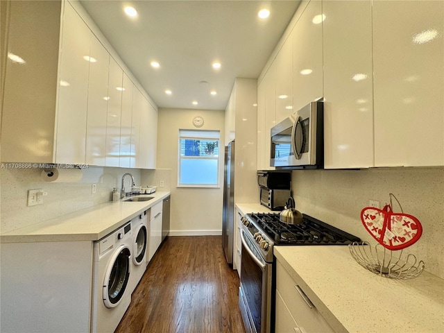 kitchen with washer and clothes dryer, white cabinets, sink, dark hardwood / wood-style floors, and appliances with stainless steel finishes