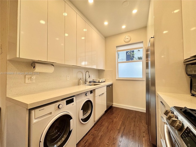 kitchen featuring white cabinetry, sink, washing machine and dryer, dark hardwood / wood-style flooring, and appliances with stainless steel finishes