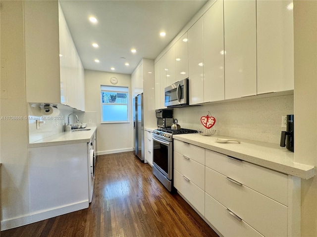 kitchen with white cabinetry, sink, tasteful backsplash, dark hardwood / wood-style flooring, and appliances with stainless steel finishes