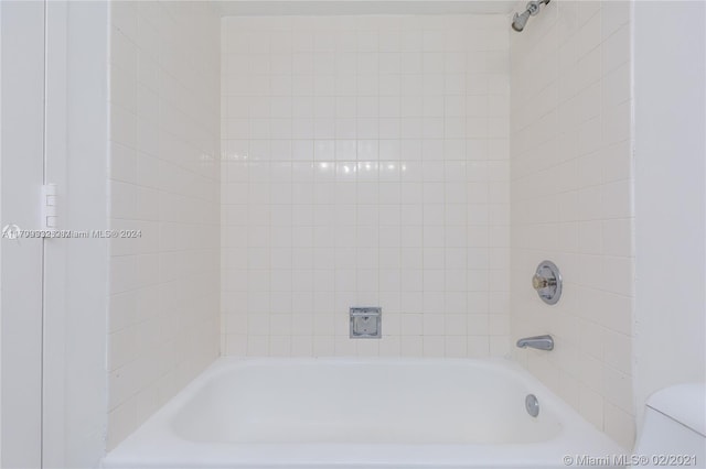 bathroom featuring tiled shower / bath combo and toilet