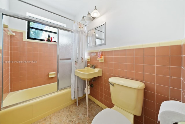 bathroom with toilet, combined bath / shower with glass door, and tile walls