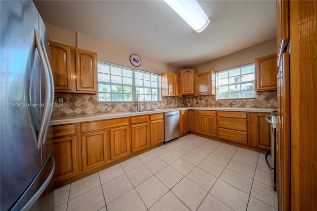 kitchen with light tile patterned flooring, appliances with stainless steel finishes, backsplash, and sink