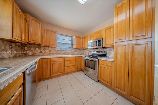 kitchen with backsplash, tile countertops, light tile patterned floors, and stainless steel appliances