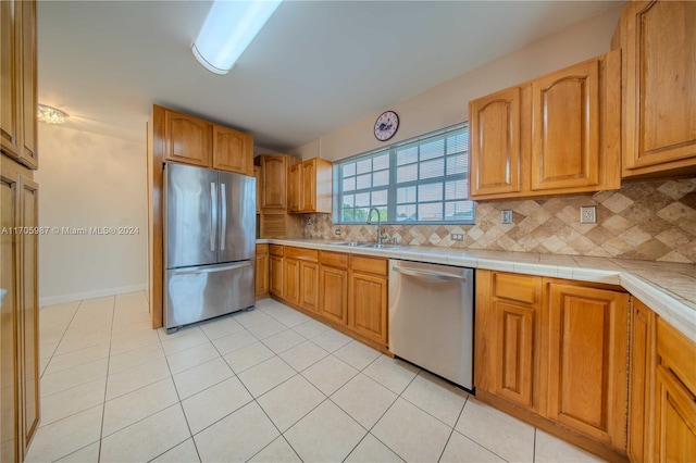 kitchen with backsplash, light tile patterned flooring, sink, and stainless steel appliances