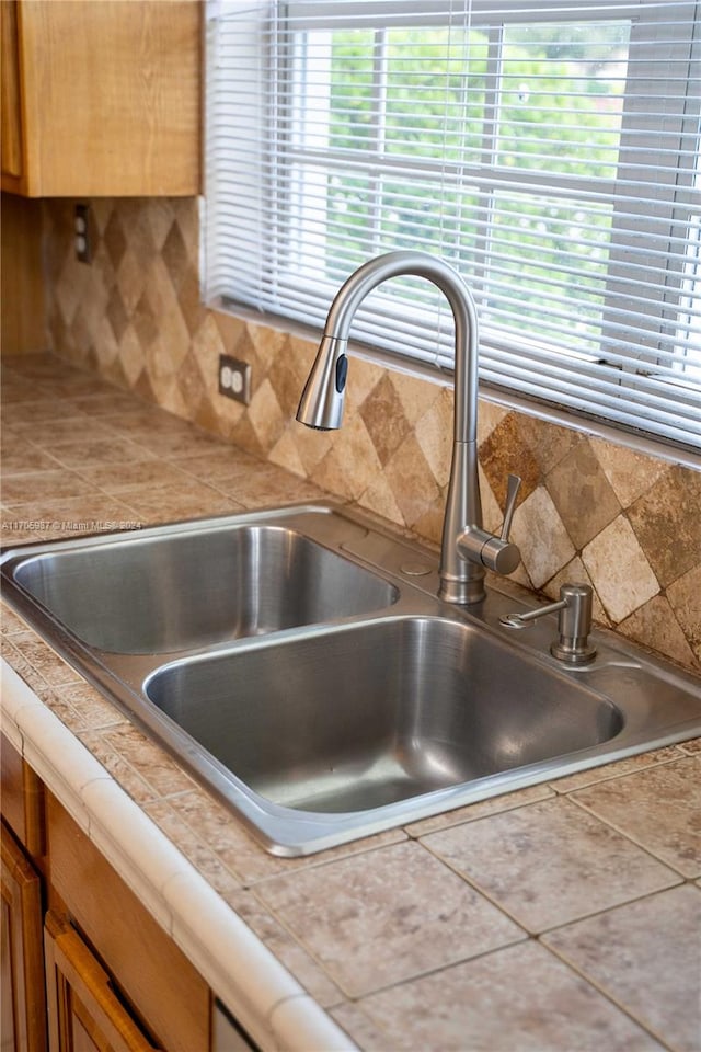 room details featuring decorative backsplash, tile counters, and sink