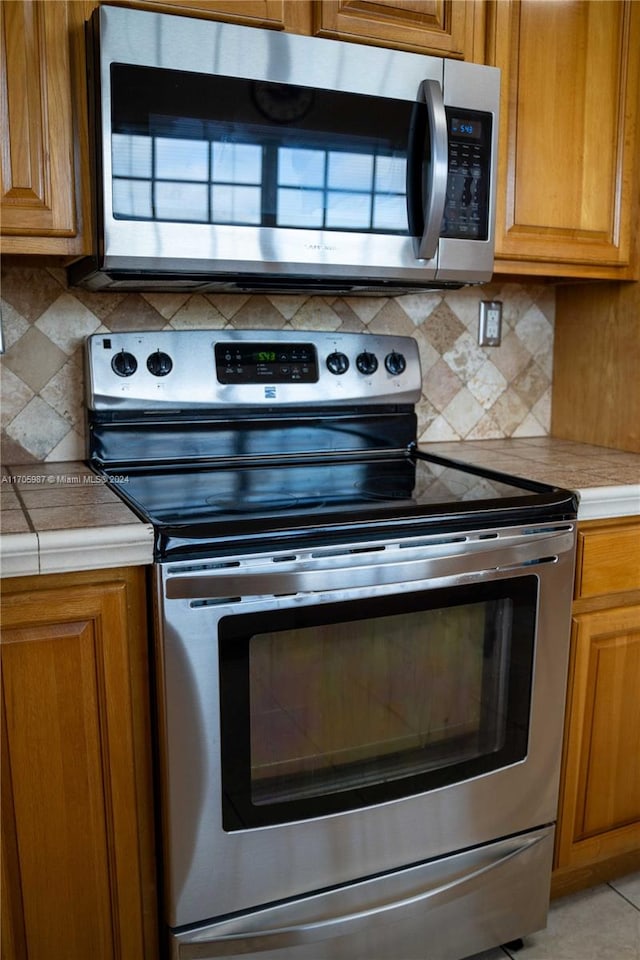 kitchen featuring light tile patterned floors, backsplash, and appliances with stainless steel finishes