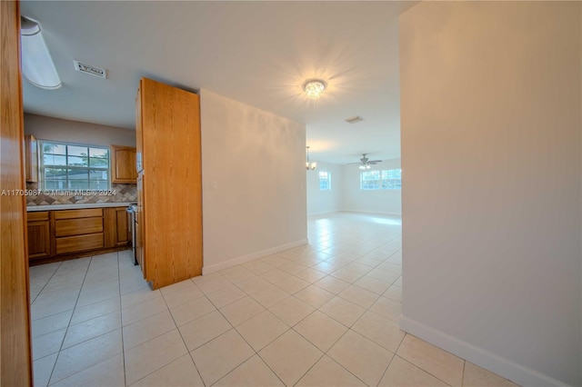 spare room featuring a wealth of natural light, ceiling fan, and light tile patterned floors