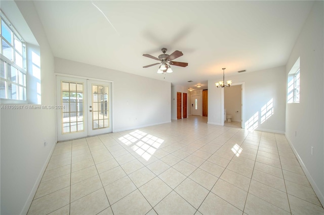 spare room featuring ceiling fan with notable chandelier, light tile patterned floors, and french doors