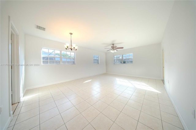 spare room featuring light tile patterned floors, ceiling fan with notable chandelier, and plenty of natural light