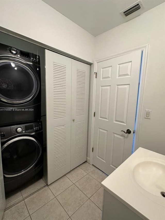 laundry area with light tile patterned flooring, sink, and stacked washer and clothes dryer