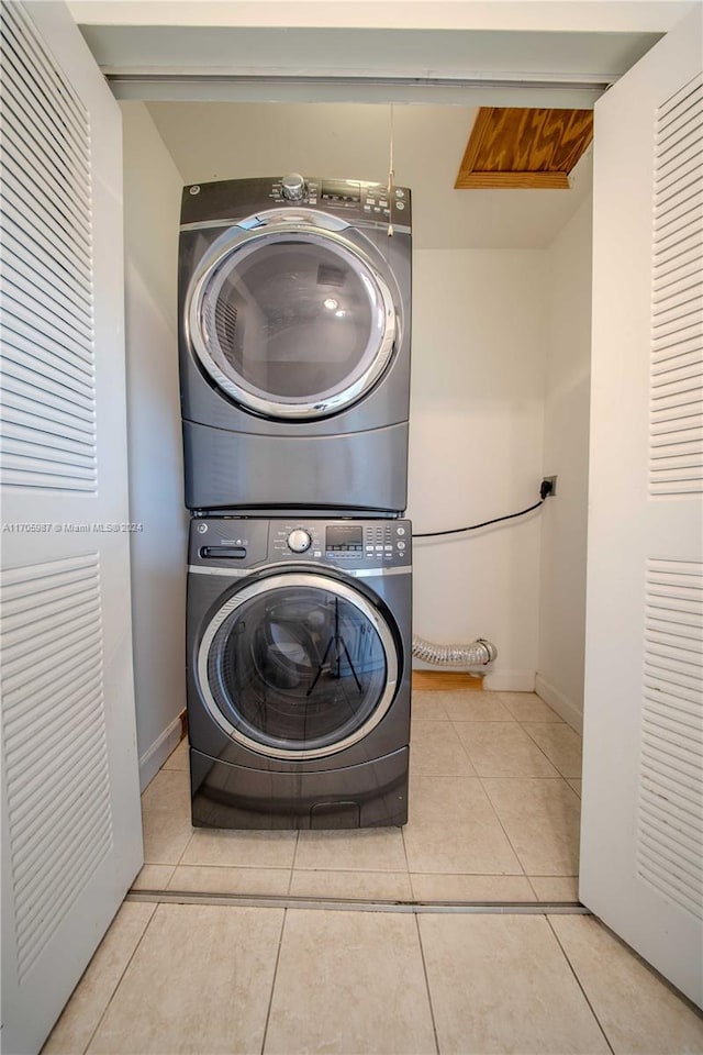 washroom with light tile patterned floors and stacked washer / drying machine