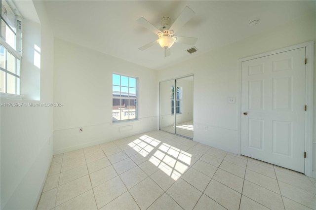 unfurnished bedroom featuring ceiling fan, light tile patterned floors, and a closet