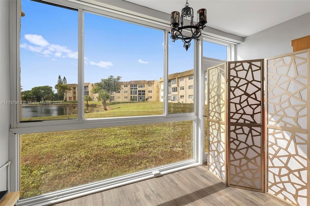 unfurnished sunroom featuring a water view and an inviting chandelier