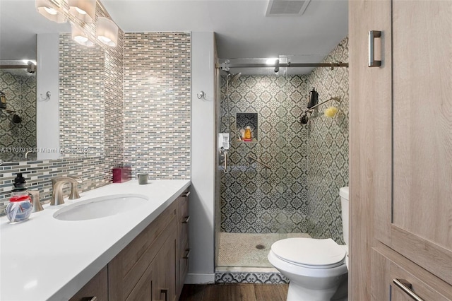 bathroom with vanity, a shower with door, backsplash, toilet, and wood-type flooring