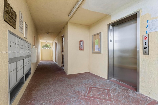 hallway featuring carpet flooring, mail boxes, and elevator