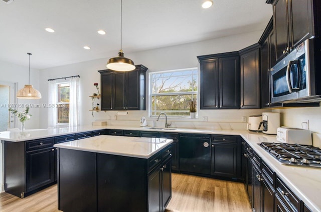 kitchen with a center island, sink, stainless steel appliances, and hanging light fixtures