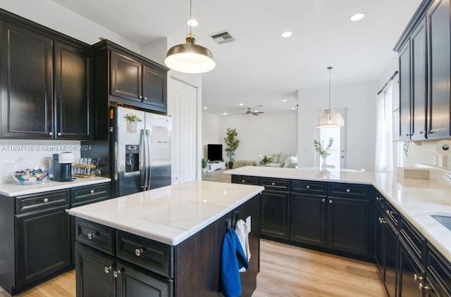 kitchen with ceiling fan, pendant lighting, light hardwood / wood-style flooring, stainless steel fridge with ice dispenser, and a kitchen island