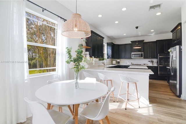 kitchen featuring hanging light fixtures, appliances with stainless steel finishes, kitchen peninsula, and plenty of natural light