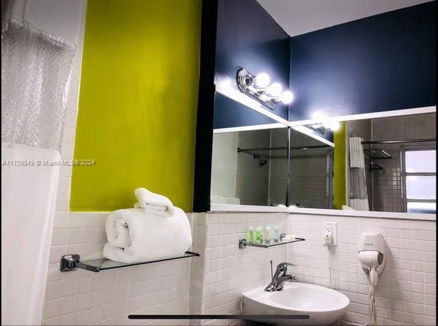 bathroom featuring tiled shower, tile walls, and sink