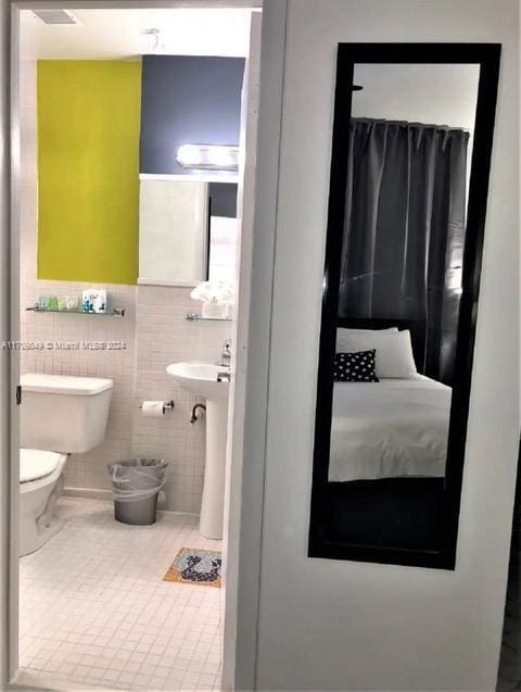 bathroom with tile patterned flooring, toilet, and tile walls