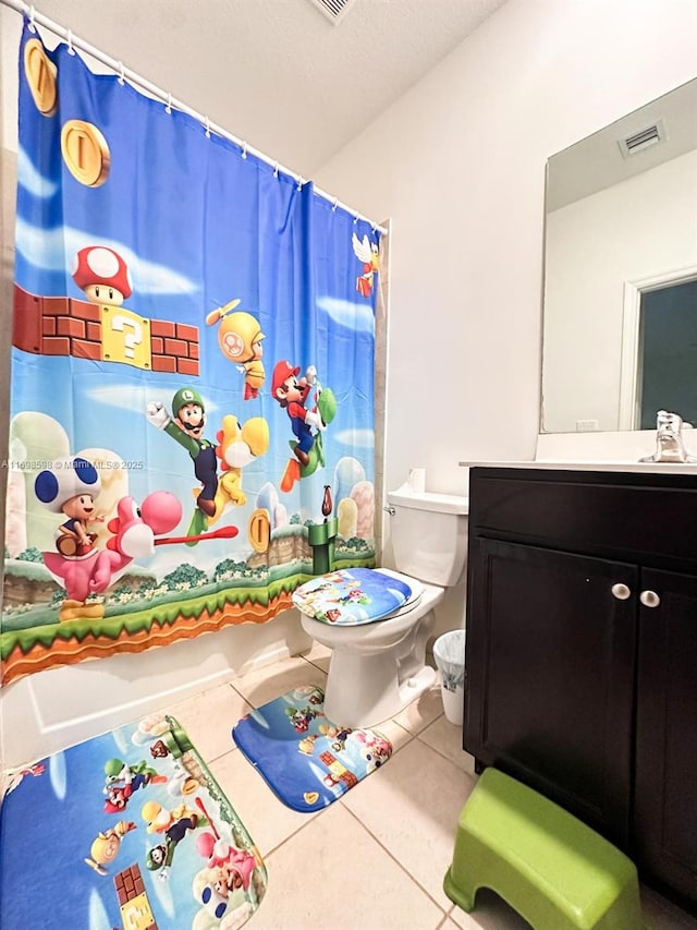 bathroom featuring tile patterned flooring, vanity, toilet, and walk in shower