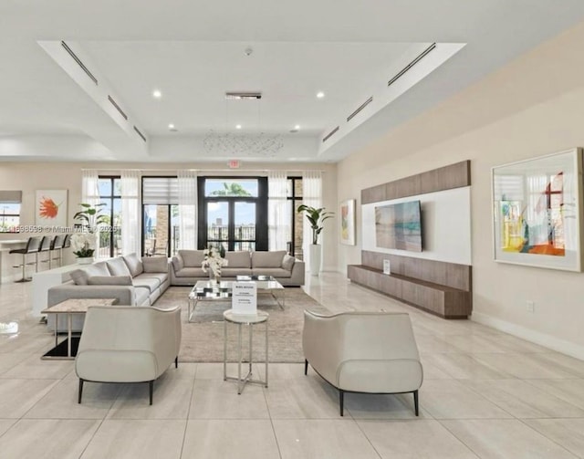 living room featuring a raised ceiling and light tile patterned floors