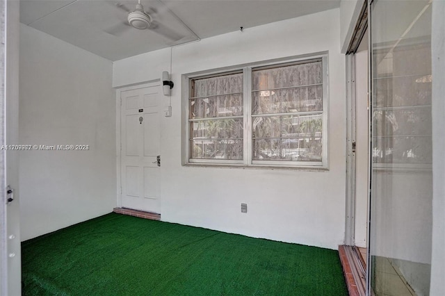 spare room with ceiling fan and dark colored carpet